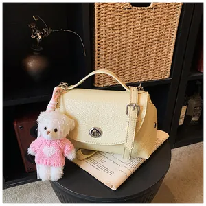 Close-up of vintage yellow pebbled leather crossbody bag with cute teddy bear charm detail.