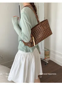 Model carrying a stylish large brown woven hollow-out tote bag in a cozy indoor setting