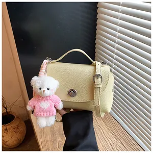Detailed view of a yellow vintage textured square crossbody bag with a cute bear charm