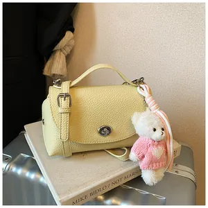 Detailed view of yellow vintage handbag with textured leather and cute bear charm