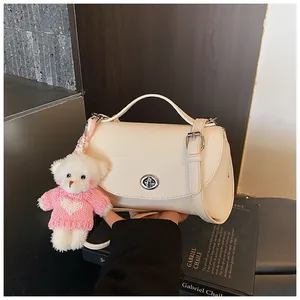 Detailed view of cream vintage crossbody bag with cute bear charm and silver lock