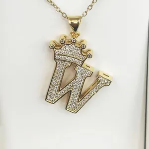 Detailed close-up of gold crown letter W pendant encrusted with sparkling zircons