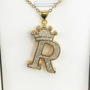 Detailed macro view of a gold-plated crown initial R pendant encrusted with clear zircons