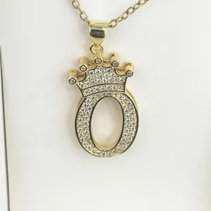 Close-up of a gold-plated letter O pendant with crown and shimmering cubic zirconia stones
