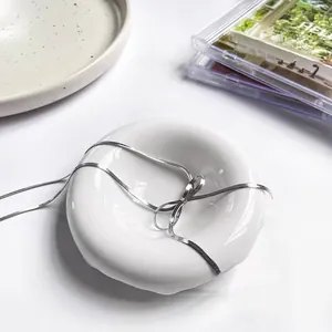 Elegante zilveren slangenschakelketting gestrikt op een witte keramische sieradenschaal
