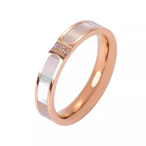Close-up of rose gold ring with three-stone setting and white shell inlay detail