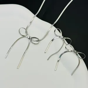 Elegante zilveren sieradenset met strik en lange kwastjes op een minimalistische achtergrond.