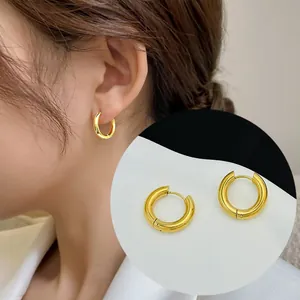 Detail of 18K gold plated titanium steel hoop earrings on model and white surface