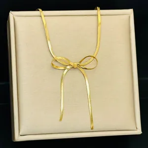 Elegante gouden strik ketting met platte slangenketting op een luxe juwelendoos