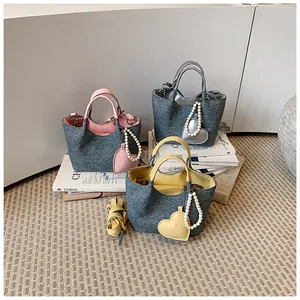 Collection of three stylish contrast color bucket bags with heart charms and pearl straps.