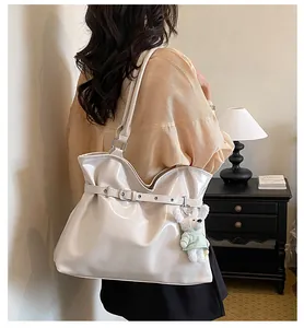 Gros plan sur un grand cabas minimaliste en cuir verni blanc crème avec charme d'ours