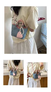 Detailed view of a trendy color-block bucket bag featuring a heart charm and pearl strap