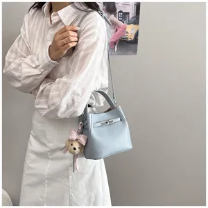 Primer plano de un elegante bolso cubo de cuero azul claro con un colgante de osito.