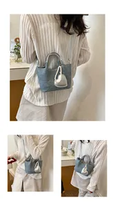 Detail of a light blue denim bucket bag with pearl heart charm and silver handles