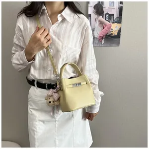 Elegante bolso de cubo en cuero granulado amarillo claro con amuleto de oso al hombro