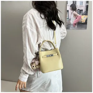 Vista detallada de un elegante bolso cubo amarillo pálido con un suave osito peluche