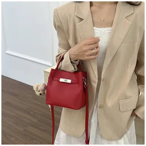 Elegante bolso de cubo en cuero granulado rojo con asa superior y correa de bandolera