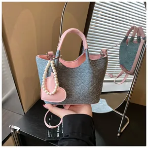 Close-up of stylish denim and pink bucket bag with a pearl heart charm accessory