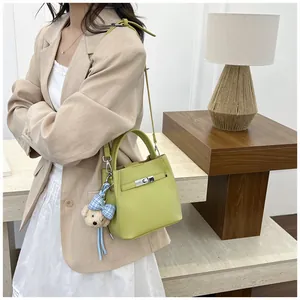 Elegante bolso bombonera verde lima con amuleto de oso, llevado con blazer beige.