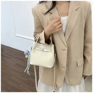 Primer plano de un elegante bolso cubo crema con cierre metálico llevado por modelo