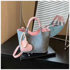 Close-up detail of the denim texture and pearl heart charm on a pink bucket bag