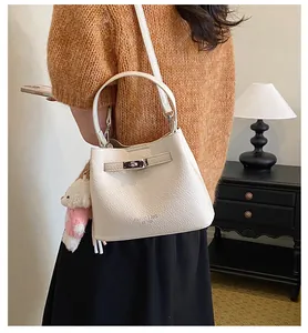 Elegant white textured leather bucket bag with a cute white bear plush charm on model