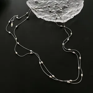 Vintage style layered silver necklace with metallic bead accents on a dark surface