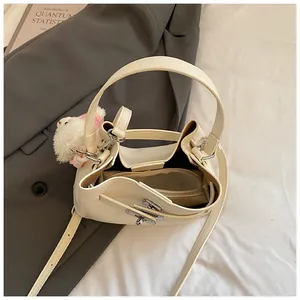 Top-down view of cream bucket bag interior with metallic hardware and bear charm