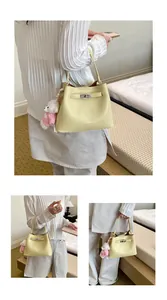Elegant light yellow leather bucket handbag featuring a cute plush bear charm for women