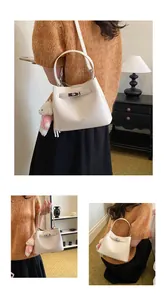 Close-up detail of a cream textured leather bucket bag featuring a cute bear charm