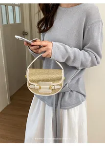 Detail of a chic straw woven saddle bag held by a woman in a cozy indoor setting