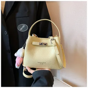 Close-up of a cream yellow pebble grain bucket bag featuring a cute bunny plush charm