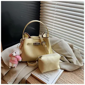 Detail view of a pale yellow pebbled leather bucket bag with matching pouch and bear charm.