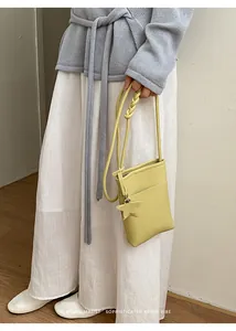 Detailansicht einer gelben minimalistischen Umhängetasche, getragen von einem Model