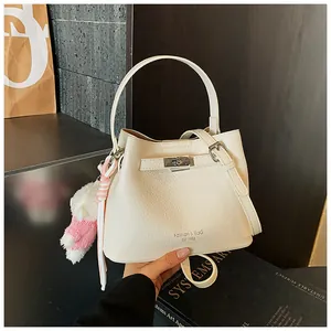Elegant white pebble leather bucket bag featuring a silver lock and plush bear charm
