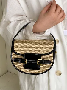 Women's straw woven saddle bag with black leather trim and gold buckles for vacation
