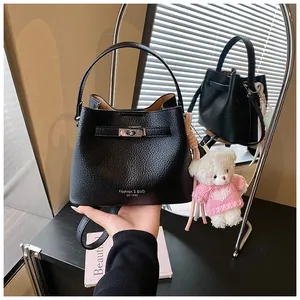 Black pebbled leather bucket bag with silver turn-lock and cute teddy bear keychain