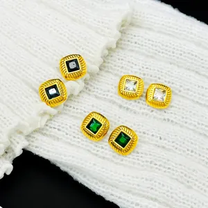 Close-up of French retro threaded gold earrings with black, green, and clear stones.