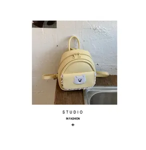 Detailed view of a cute yellow mini backpack for women with lace trim and bear patch.