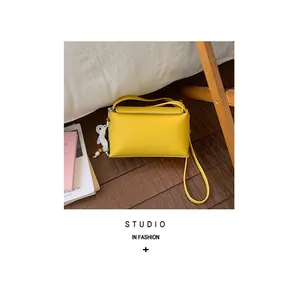 Borsa a tracolla piccola e quadrata gialla minimalista in un contesto lifestyle.