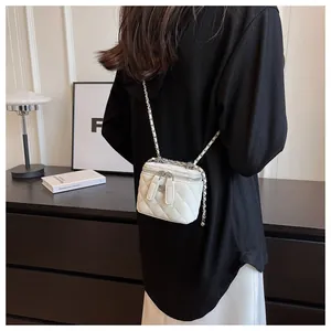 Back view of a model wearing a stylish white quilted mini box bag with a silver chain strap.