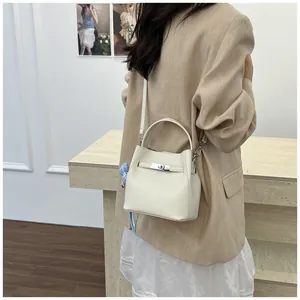 Vista detallada de un elegante bolso de cubo en cuero crema con cierre plateado fino