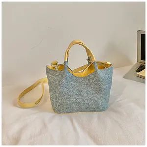 Stylish color-block denim bucket bag with yellow handles and crossbody strap