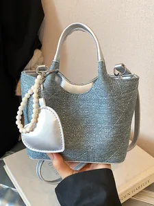 Blue denim bucket bag with silver metallic trim and decorative heart charm accessory