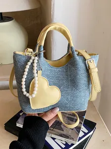 Stylish blue denim bucket bag with yellow contrast trim and pearl heart charm accessory