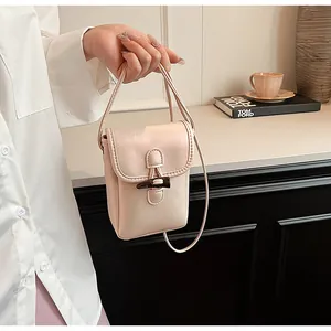 Detail of a stylish cream mini crossbody bag with a toggle horn buckle and top handle.