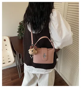 Back view of a woman wearing a stylish pink bucket bag with a cute bear charm