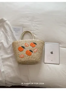 Handgemaakte strooien tas met oranje borduursel naast een iPad voor de afmetingen
