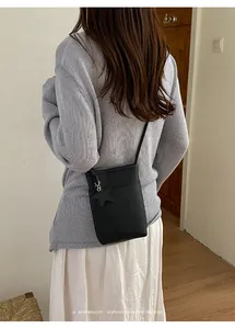 Minimalistische schwarze Umhängetasche für Handys mit Sternanhänger im Alltagsoutfit