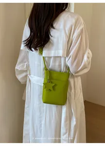 Nahaufnahme einer lindgrünen Handytasche aus genarbtem Leder, getragen von einem Model.